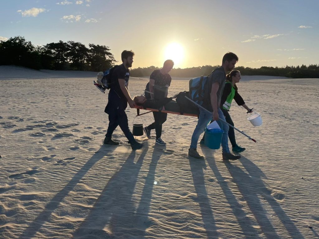 Presteren onder druk training. Deelnemers lopen buiten door het zand met een patiënt.